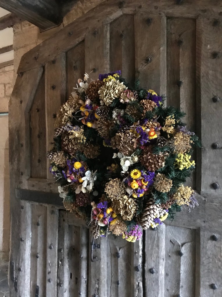 A large, dried flower Christmas wreath on the front door at Baddesley Clinton, Warwickshire 